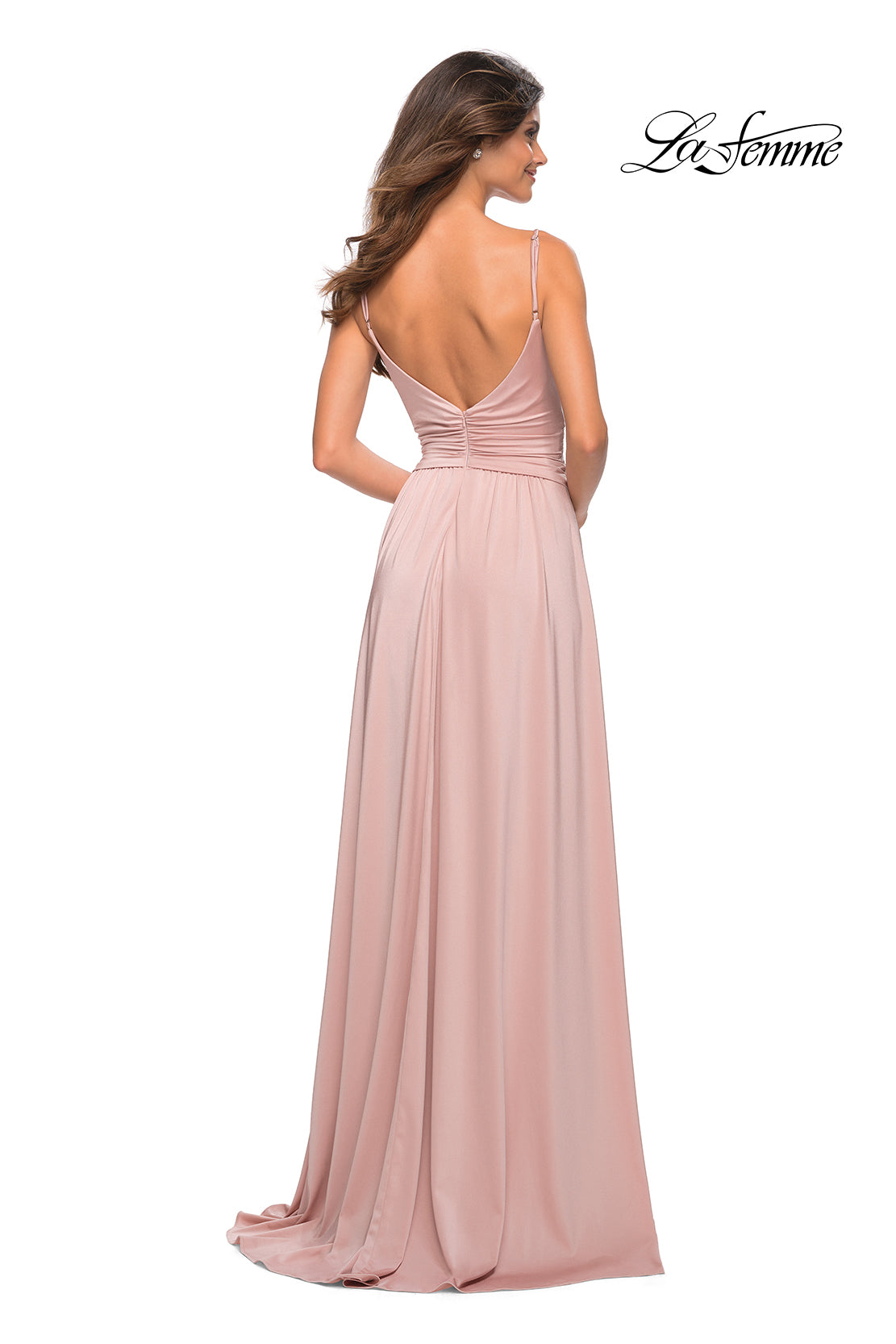 A woman stands facing away, wearing the La Femme Simple Elegant Long Formal Prom Dress in light pink, featuring a deep V-back and thin straps. The